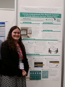 Emilia standing in front of poster titled "Trainng Undergraduate Peer Research Assistants to Provide Reference Services" 